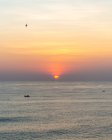 Vue spectaculaire sur la mer calme ondulant sous un ciel couchant coloré et un soleil orange vif à Uluwatu — Photo de stock