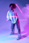 Confident young African American female dancer with curly hair standing looking away in neon lights — Stock Photo