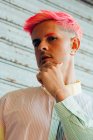 De baixo auto confiante pensativo jovem gay na moda vestuário com cabelo rosa e tatuagens olhando para a câmera — Fotografia de Stock