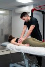 Невихований чоловік-фізіотерапевт масажує спину анонімної жінки на ліжку під час медичної процедури в лікарні — стокове фото