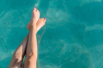 Анонімні босоніжки, які торкаються блискучої витягнутої води в басейні під час подорожі — стокове фото
