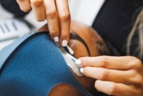 Crop unrecognizable beauty technician with cotton bud preparing ethnic woman with patch for eyelash extension procedure in salon — Fotografia de Stock
