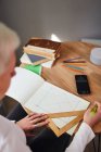 Сверху неузнаваемая женщина-астролог рисует на бумаге с треугольником и ручкой за столом — стоковое фото