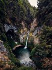 Spectacular drone view of powerful stream of waterfall flowing in lake in mountainous forest — Stock Photo