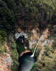 Spektakuläre Drohnen-Ansicht mächtiger Wasserfall fließt in See in bergigem Wald — Stockfoto