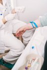 Dall'alto del raccolto medico irriconoscibile in uniforme preparare il paziente con laccio emostatico per la procedura endovenosa in ospedale — Foto stock