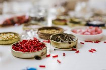 Vista lateral de varias perlas decorativas en recipientes de metal sobre mesa de madera - foto de stock