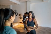 Allegro femmine multirazziali in abbigliamento sportivo in piedi in studio di yoga e parlando tra loro dopo la classe — Foto stock