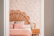 Confortável bonito natural vintage rattan cabeceira cama com almofadas ornamentais em um quarto — Fotografia de Stock