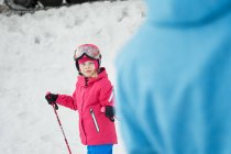 Faceless parent in warm sportswear teaching little kid to ski alongside snowy hill slope in winter ski resort — Stock Photo