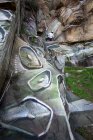 Vue de dos corps complet du peintre avec peinture en aérosol faisant graffiti accroché à la corde sur pente rocheuse raide — Photo de stock
