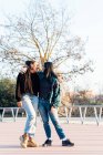 Smiling diverse lesbian girlfriends in trendy wear embracing and speaking while looking at each other on walkway — Stock Photo
