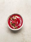 Top view of bowl of sweet cold berry soup garnished with pistachios served on cutting board on table — Stock Photo