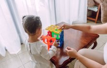 Side view of crop woman and little girl playing together with learning toy at home — Stock Photo