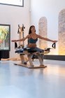 Konzentriert durchtrainierte weibliche Dehnbeine und Ausfallübungen auf dem Pilates-Reformer beim Training im Fitnessstudio — Stockfoto
