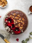 Сверху сладкий шоколадный торт украшенный красными цветами и грецкими орехами подается на столе — стоковое фото