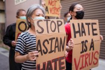 Ativistas étnicos com inscrições I Am Not A Virus e One Race em cartazes durante o movimento Stop Asian Hate na cidade — Fotografia de Stock