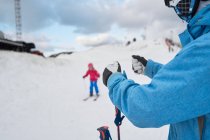 Parent sans visage en vêtements de sport chauds apprenant aux petits à skier le long de la pente enneigée de la station de ski d'hiver — Photo de stock