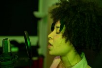 Черная певица исполняет песню против микрофона с поп-фильтром, стоя и закрывая глаза в звукозаписывающей студии — стоковое фото
