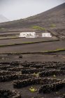Modern white residential house located in middle of black lands against hills in haze — Fotografia de Stock
