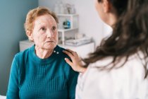 Crop médico anônimo falando com mulher idosa triste assustado enquanto olha um para o outro durante o exame no hospital — Fotografia de Stock