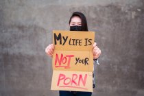 Femme ethnique en masque de protection debout avec Ma vie n'est pas votre carton porno affiche pendant la protection contre le harcèlement sexuel et les agressions — Photo de stock