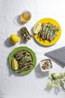 From above of delicious fried anchovies served on plates with lemon and placed on white table with glass of beer — Photo de stock