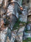 Seitenansicht Ganzkörper-Maler mit Sprühfarbe, die Graffiti am Seil am steilen Felshang hängen lässt — Stockfoto