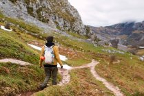 Мечтательная женщина в теплой одежде, прогуливаясь по склону горы, исследуя природу Пиков Европы в Испании — стоковое фото