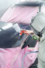Вид сбоку на мужчину в респираторной маске и автомобиль с краской защитного костюма с автоматом в эксплуатации — стоковое фото
