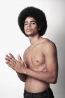 Joven hombre negro confiado con seis abdominales paquete y peinado afro mirando a la cámara sobre fondo blanco - foto de stock