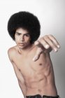 Junger selbstbewusster schwarzer Mann mit Sixpack-Bauch und Afro-Frisur, der auf weißem Hintergrund in die Kamera schaut und zeigt — Stockfoto