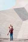 Volle Länge des männlichen Kunststücks mit Jonglierkeulen beim Stehen gegen zeitgenössische Steinbauten mit ungewöhnlicher geometrischer Architektur — Stockfoto