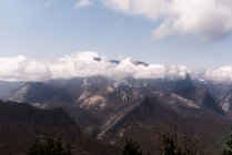 Paesaggio mozzafiato di nuvole che galleggiano sulla cresta rocciosa della montagna nella giornata di sole in estate — Foto stock