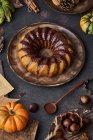 From above tasty appetizing pumpkin cake with chocolate cream on table decorated with autumn vegetables — Stock Photo