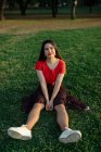 Tranquillo femminile seduto sull'erba sul prato nel parco e godersi il tramonto in estate — Foto stock