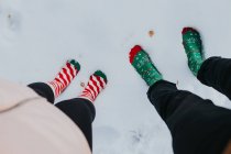 From above feet in socks of man and woman standing on snow ground — Stock Photo