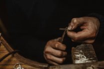 Bärtiger Goldschmied mit Zange bei der Herstellung winziger Metalldetails auf Werkbank in Werkstatt — Stockfoto