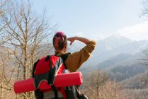 Back view of pensive female traveler with backpack standing in mountains looking away — Stock Photo