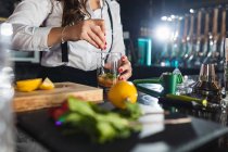 Cultivé femme barman méconnaissable dans une tenue élégante ajouter du sucre dans le verre tout en préparant cocktail mojito debout au comptoir dans le bar moderne — Photo de stock