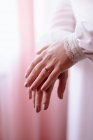 Crop unrecognizable newlywed woman in elegant white wedding dress with lace cuffs and with ring on finger standing in light room — Stock Photo