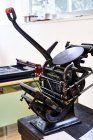 Ретро-шорсткий листпрес машина з металевими деталями розміщена на дерев'яній верстаті в типографії — стокове фото