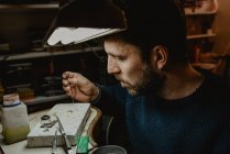 Orfèvre masculin utilisant un outil manuel pour façonner une bague en métal en atelier — Photo de stock