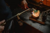 Невідомий золотошукач тане метал для ювелірних виробів з паяльною лампою, стоячи поруч з робочою лавкою в майстерні — стокове фото