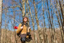 Vista laterale di zaino in spalla femminile in piedi in boschi in altopiani nella giornata di sole — Foto stock