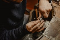 Hands of male goldsmith using manual tool to shape metal ring in workshop — Stock Photo