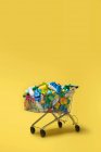 Кошик різнокольорових пластикових пакетів на жовтому фоні — стокове фото