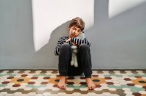 Upset lonely preteen boy victim of domestic violence sitting on floor and embracing toy — Stock Photo