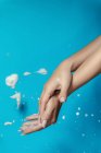 Crop anonymous female with long nails demonstrating hands with white soap foam against blue background — Stock Photo