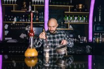 Man preparing a big glass traditional hookah in a night club — Stock Photo